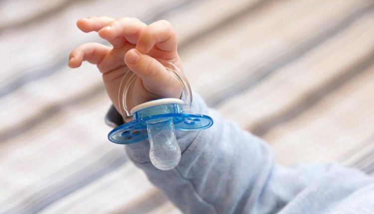 Photo of child’s hand holding a pacifier, close-up